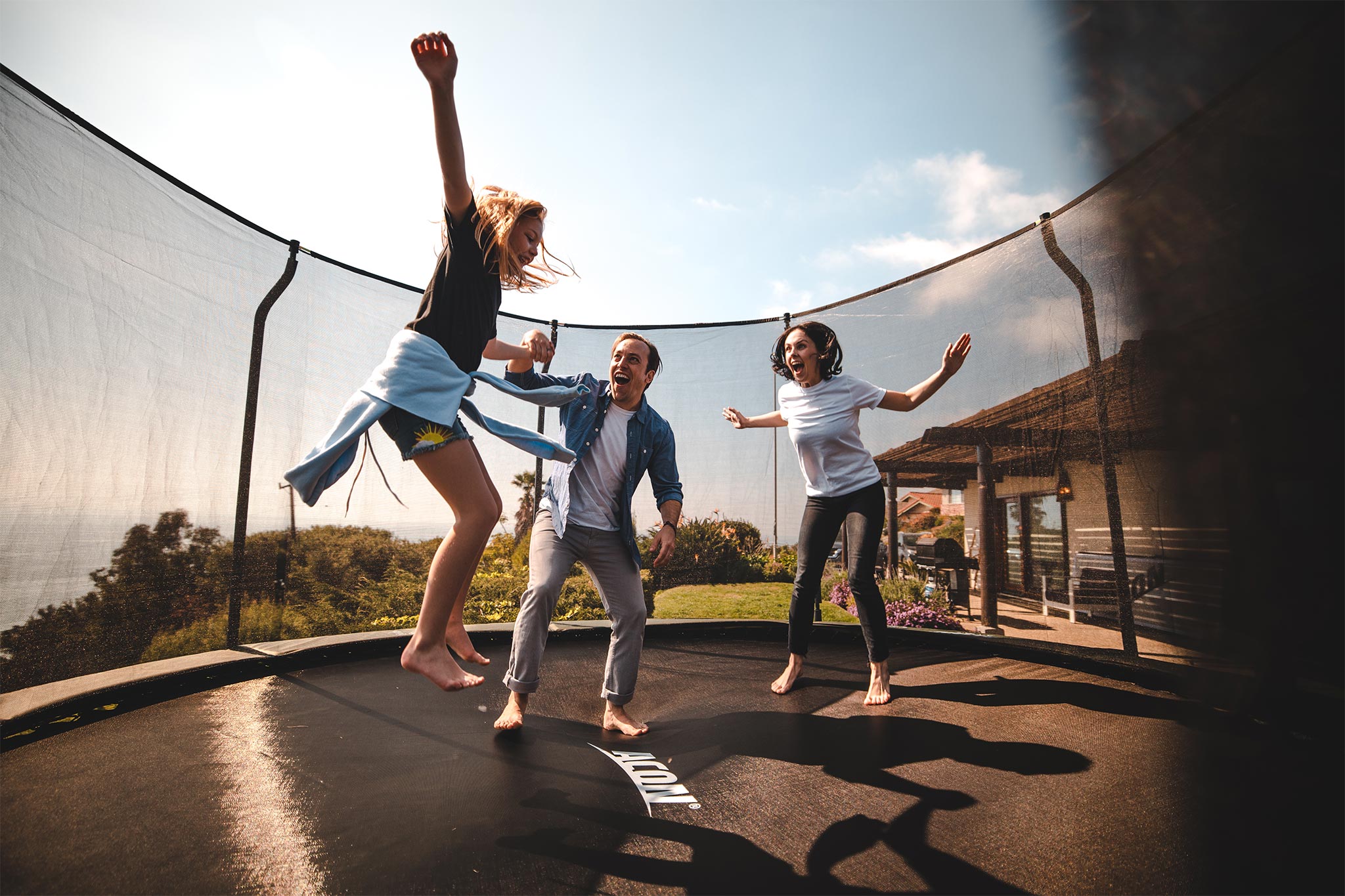 En flicka på en rund trampolin med sina föräldrar