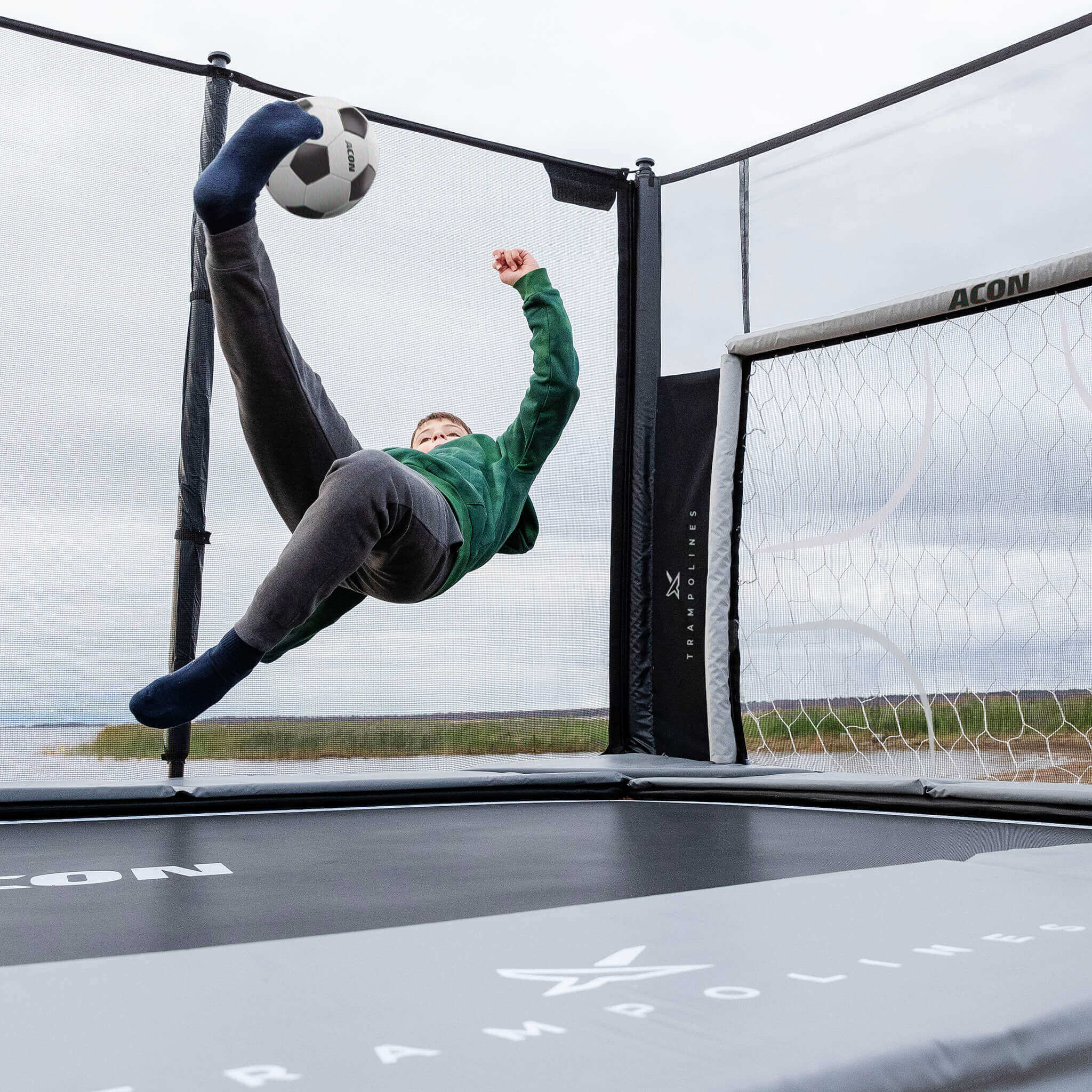 Två pojkar spelar fotboll på en Acon X 17 studsmatta med fotbollsmålning